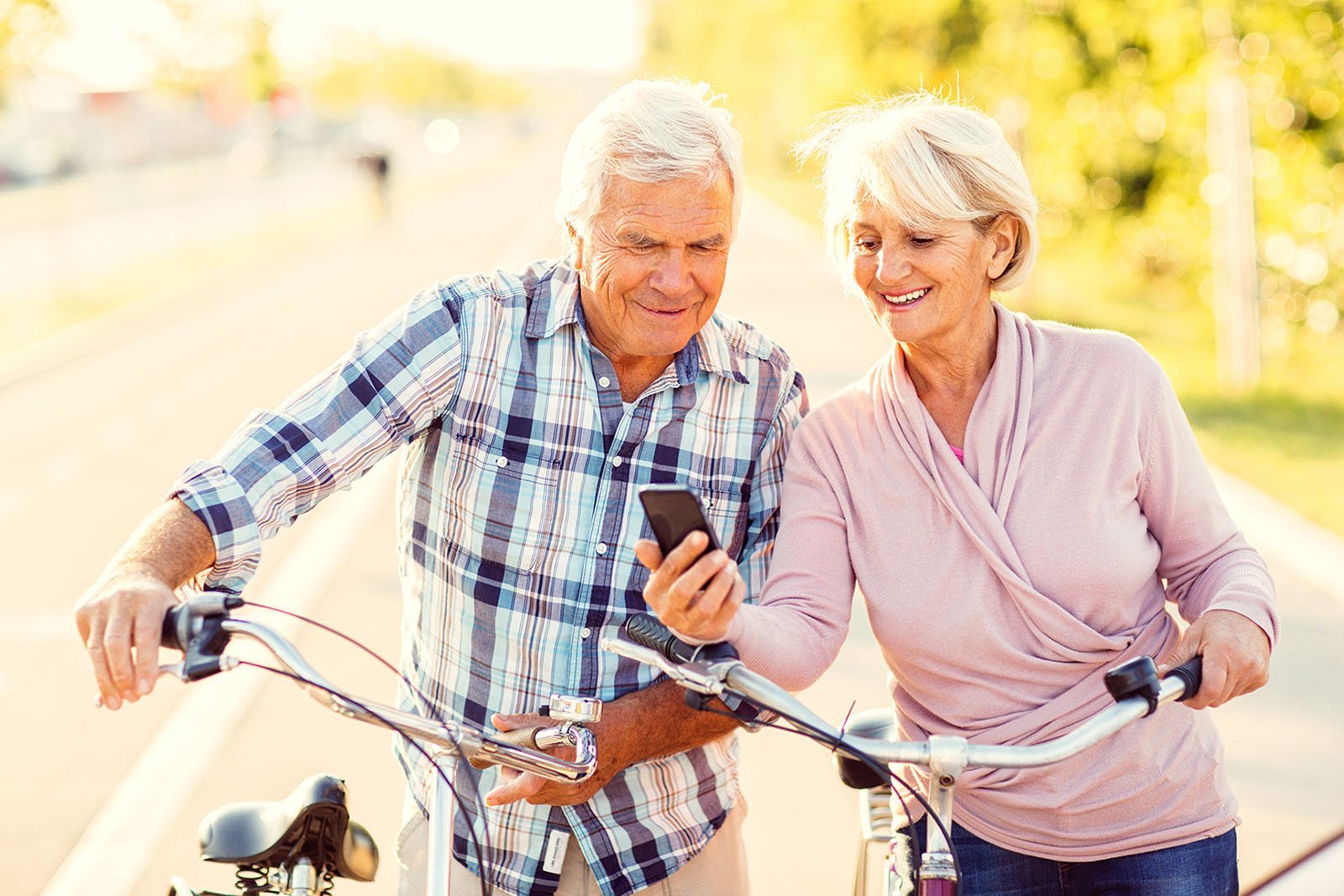 Elderly couple with bikes stopping to look at cellphone