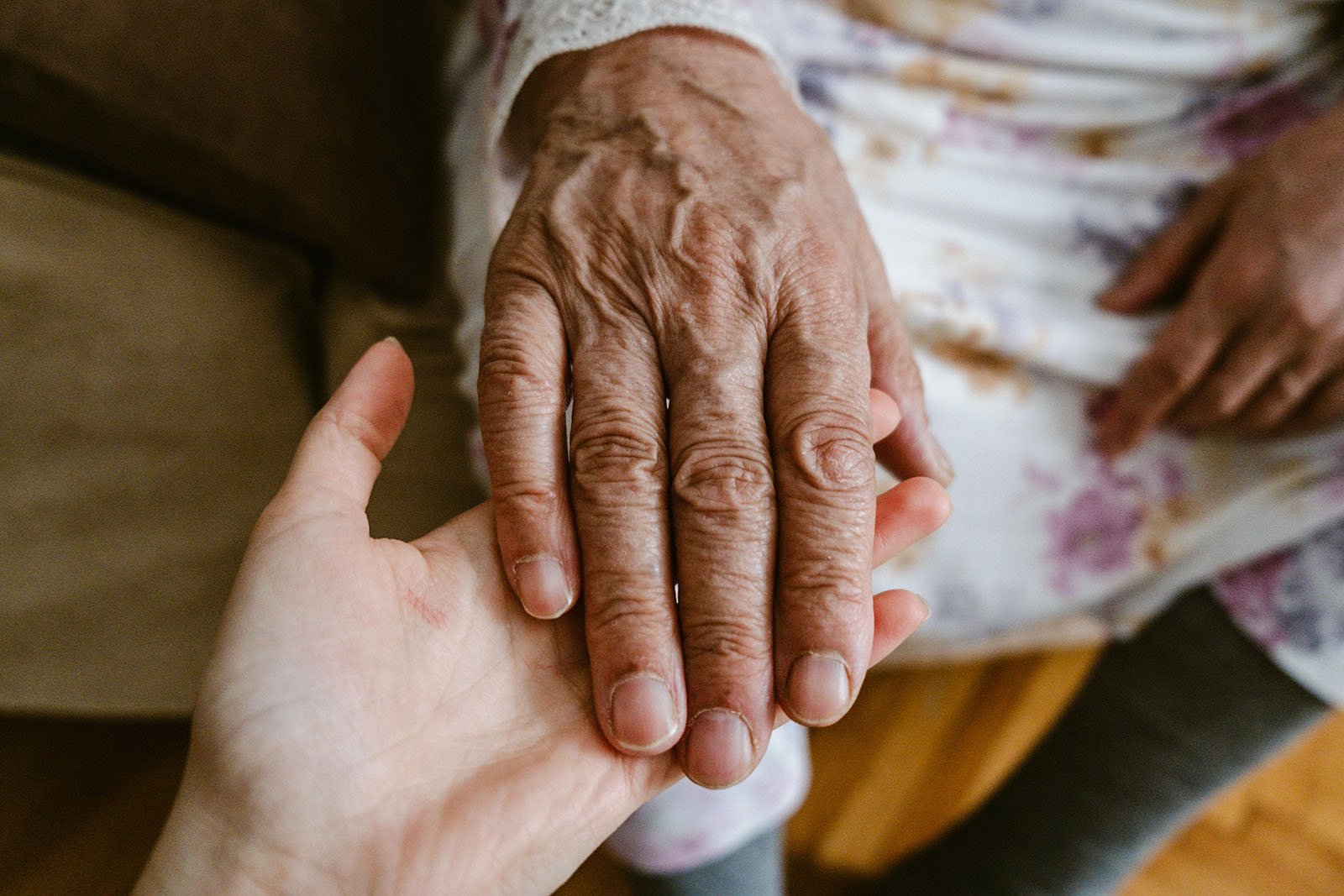 Younger person holding elderly person's hand